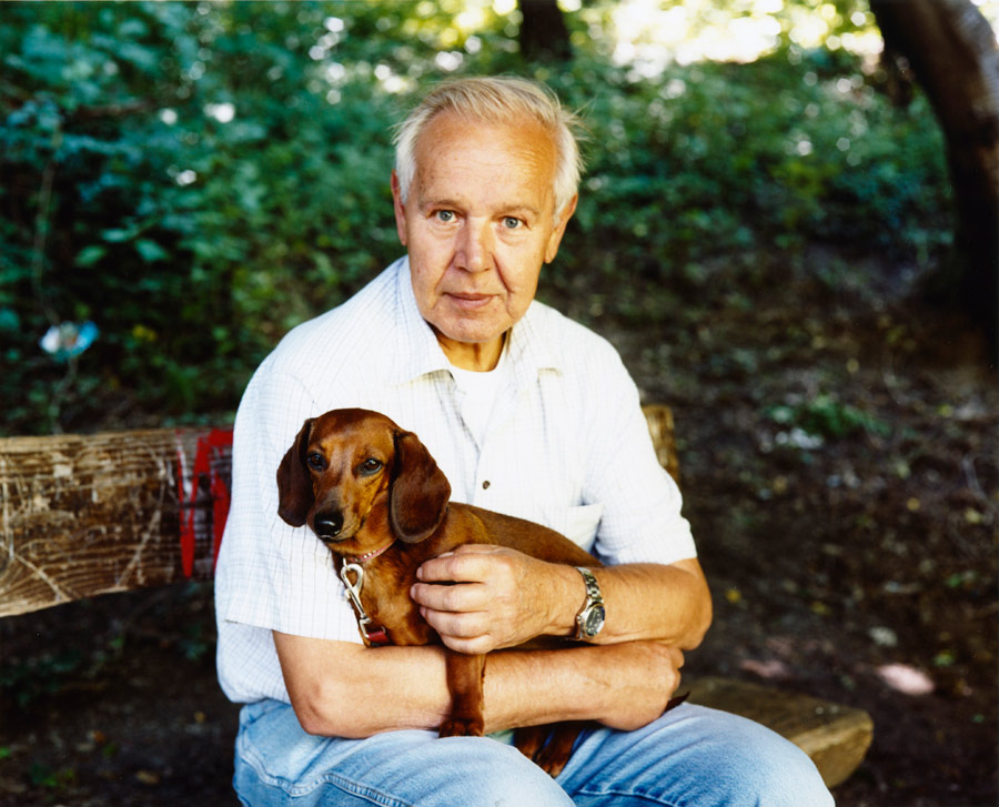 ein mann sitzt  mit seinem dackel auf einer bank im wald. // a man sits with his dachshund on a bench in the forest.