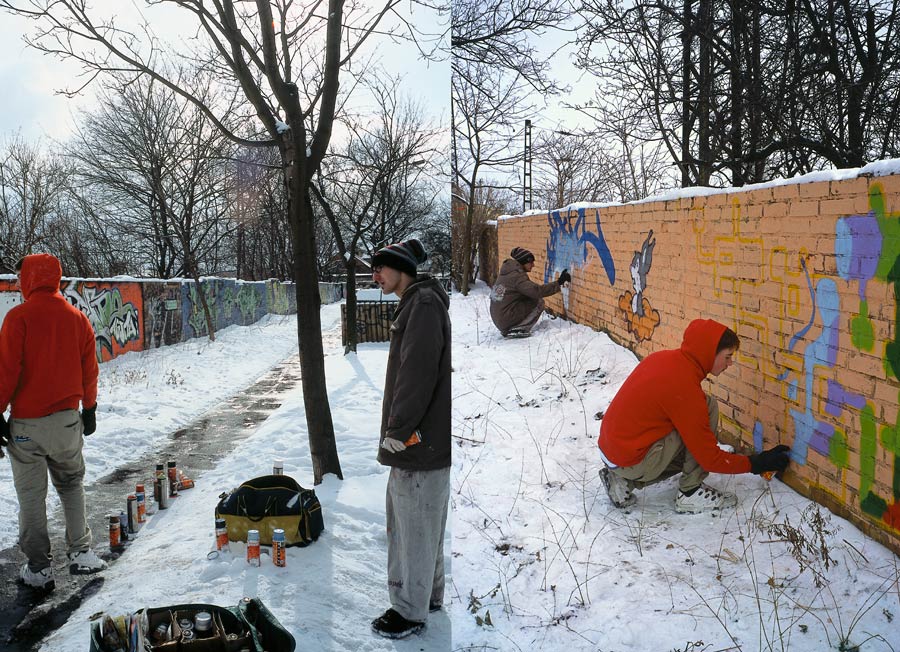 es liegt schnee und es ist kalt. junge street-art künstler bemalen eine mauer. ihre sprühdosen stehen im schnee auf dem boden. // it's snowing and it's cold. young street artists are painting a wall. their spray cans are on the ground in the snow.