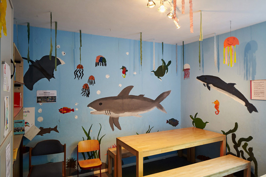 ehemaliger aufenthaltsraum für die schüler:innen - die wände sind mit einem haifisch und delphin und anderen meerestieren bemalt. daher der spitzname - das aquarium. / former pupils lounge - the walls are painted with a shark and dolphin and other sea creatures. hence the nickname - the aquarium.