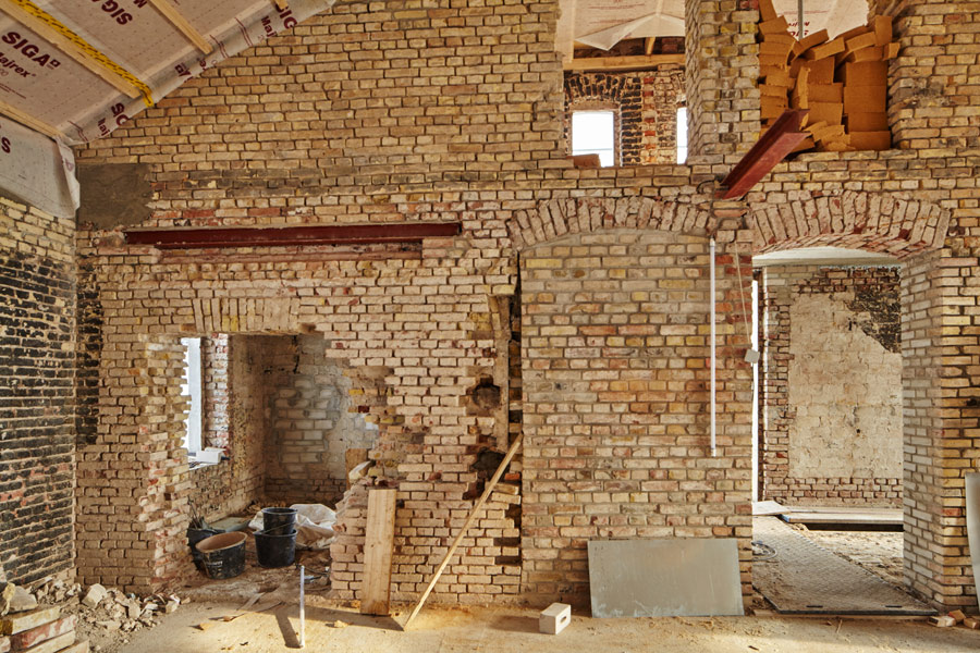 die sonne illuminiert die noch unverputzte ziegelwand // the sun illuminates the still unplastered brick wall